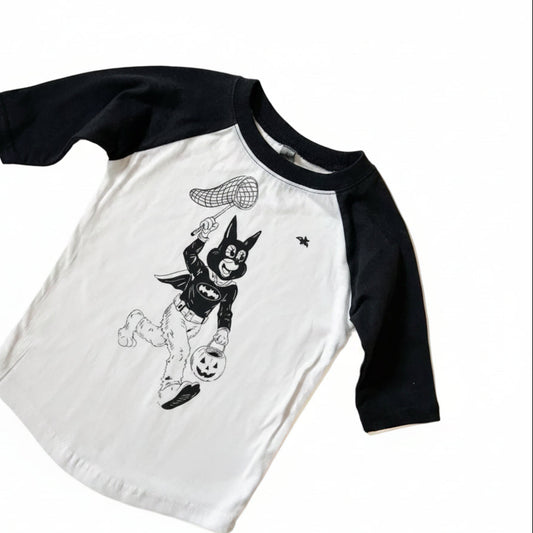 A kids' raglan baseball t-shirt with a white body and black 3/4 sleeves, featuring a black graphic of a cartoon 